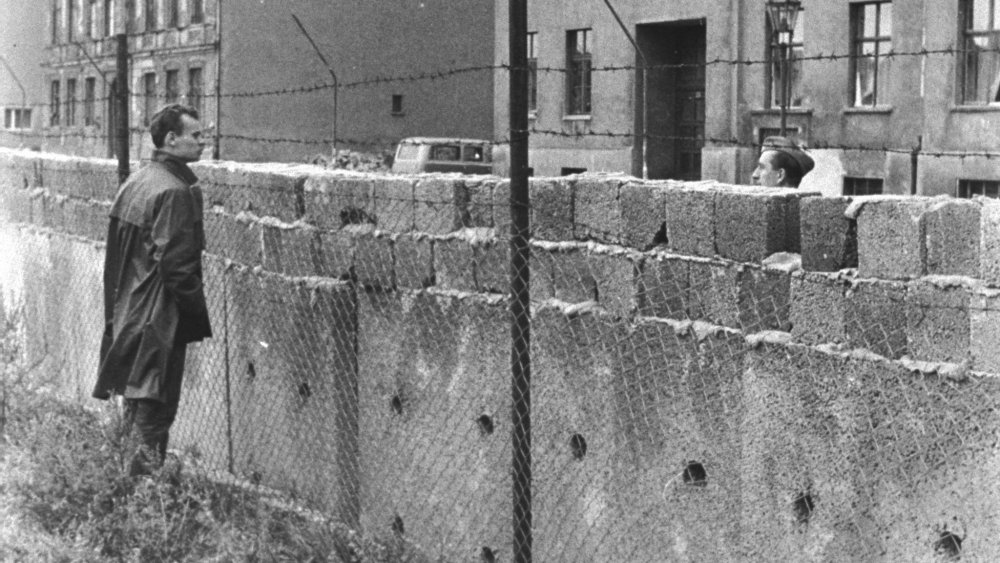 A man peers over the Berlin Wall