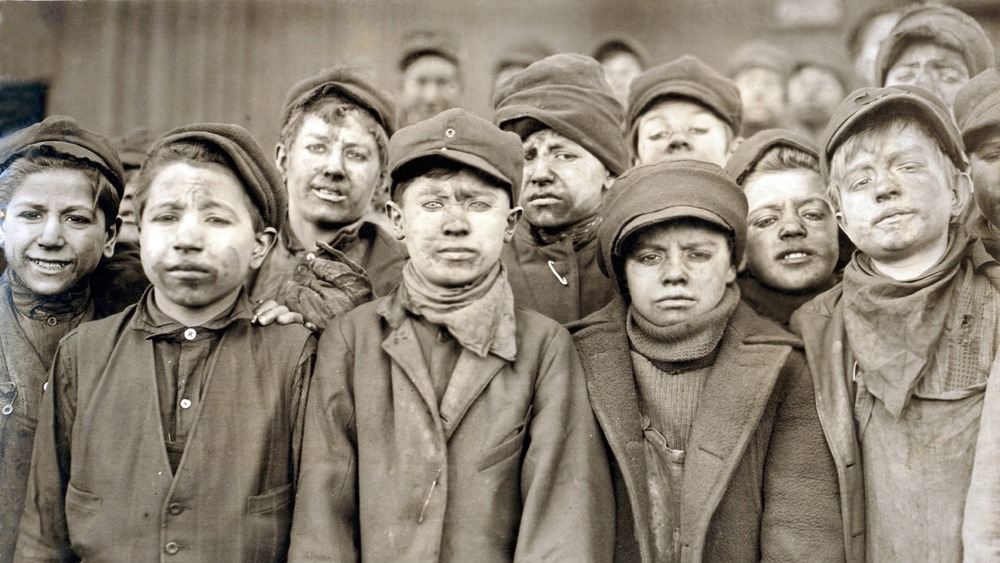 A group of dirty child laborers standing for a picture