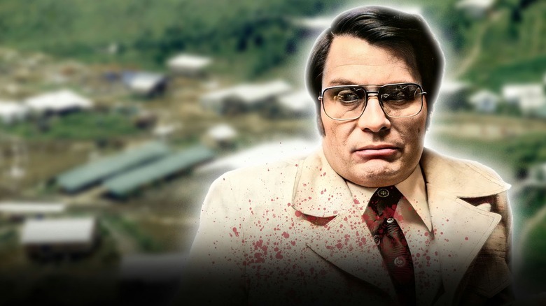 Jim Jones with blood on his clothes in front of Jonestown