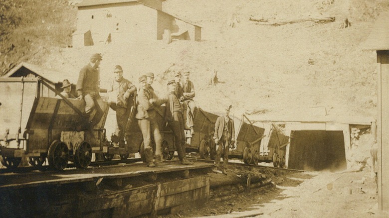 Miners leaning against coal carts