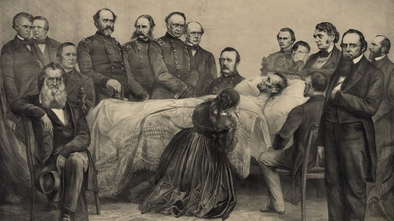 Print shows the interior of a room with Abraham Lincoln lying on a bed surrounded by cabinet members, generals, and family members