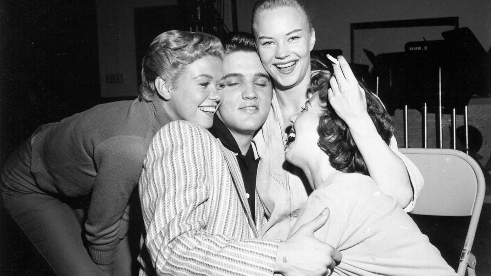 Three girls crowd around Elvis to take a photo