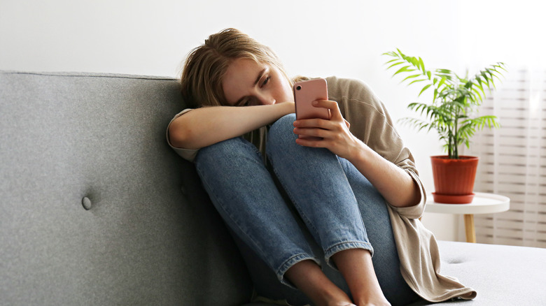 Woman sad looking at cell phone