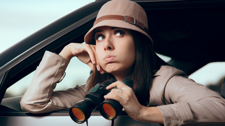 private investigator with binoculars looking bored