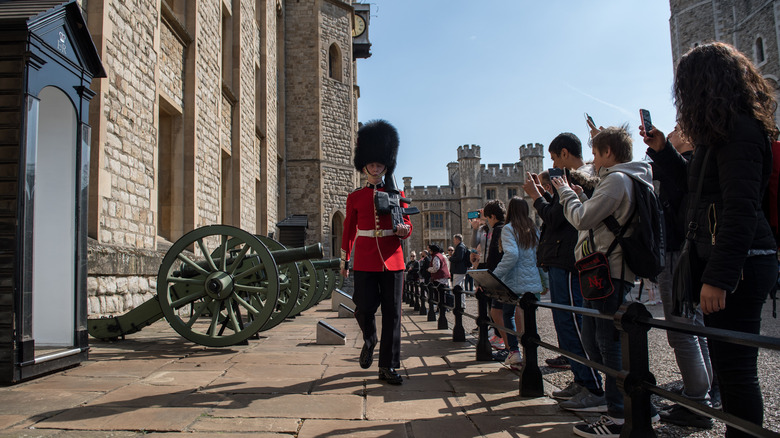 Tourists take photos of guardsman marching