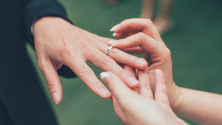 Woman's hands giving ring to male hand