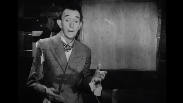 Stan Laurel in font of window 