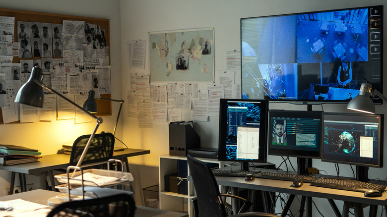 office with desk, computers, criminal records photos scattered