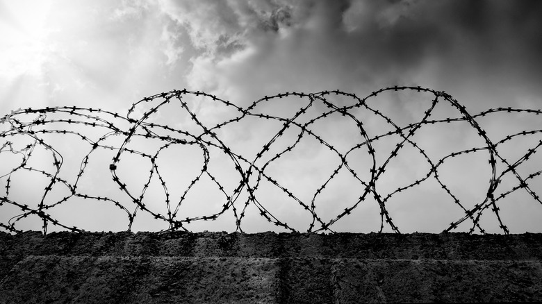 Prison wall with barbed wire and smoke