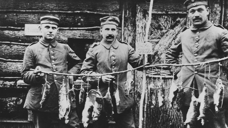 Three soldiers with caught rats