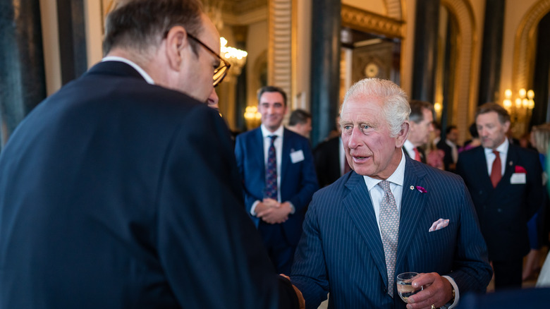 The king talking with a man at Buckingham Palace