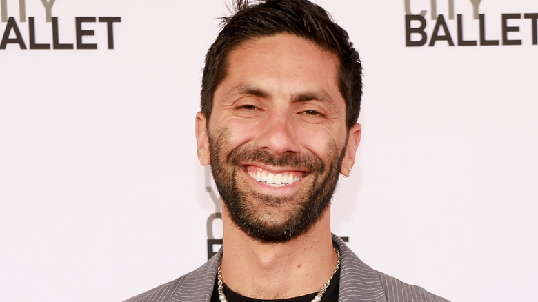 nev schulman smiling broadly wearing necklace