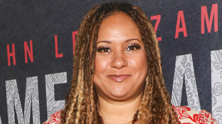 tracie thoms in braids and red print dress smirking at camera