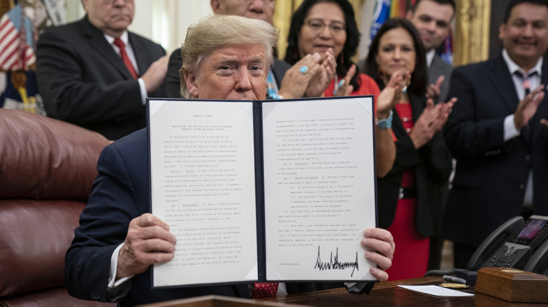 Donald Trump holds up a signed document