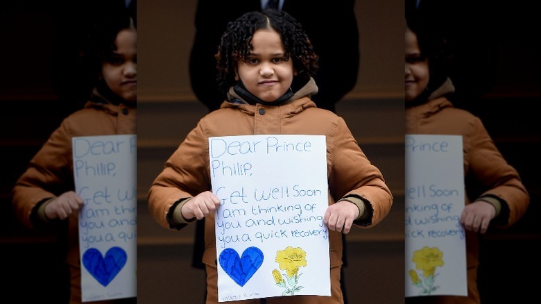 Adorable child with a card for Prince Philip outside the hospital in 2021