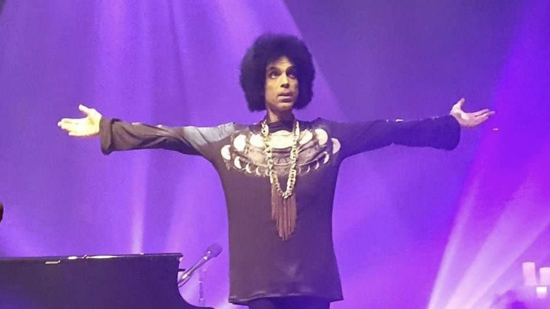 prince extends his arms during 2016 concert