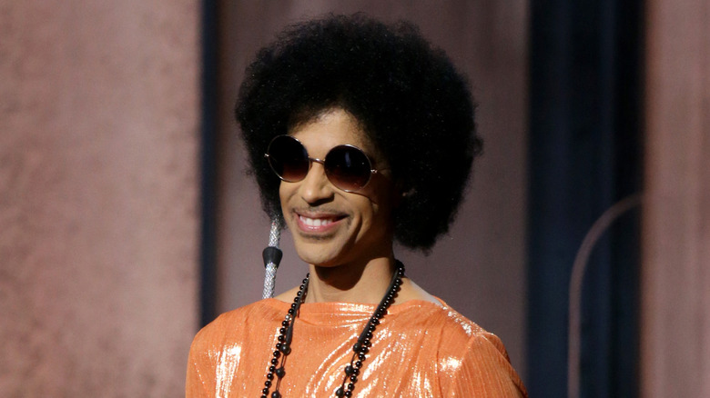 prince with afro and sunglasses smiling at 2015 grammy awards