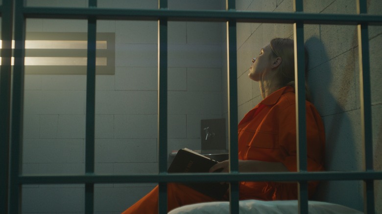 Woman reading Bible in prison cell