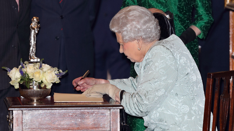 Queen Elizabeth writing away at her desk