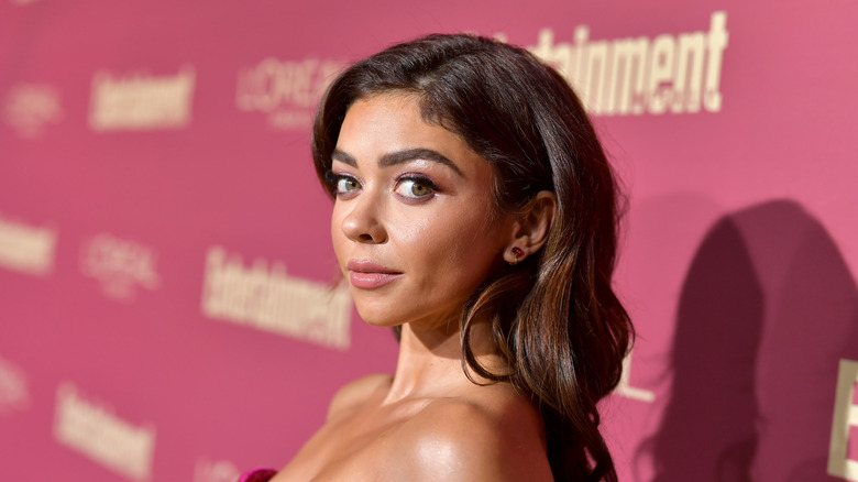 Sarah Hyland on the red carpet with a pink bacground behind her