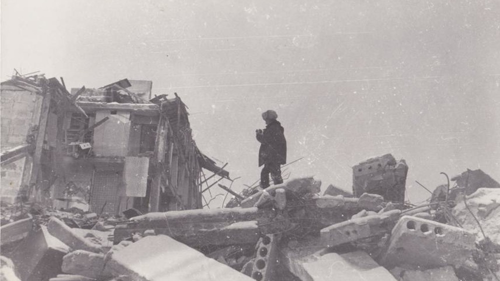 Man standing atop rubble in aftermath of the Spitak Earthquake