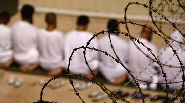 prisoners pray behind barbed wire