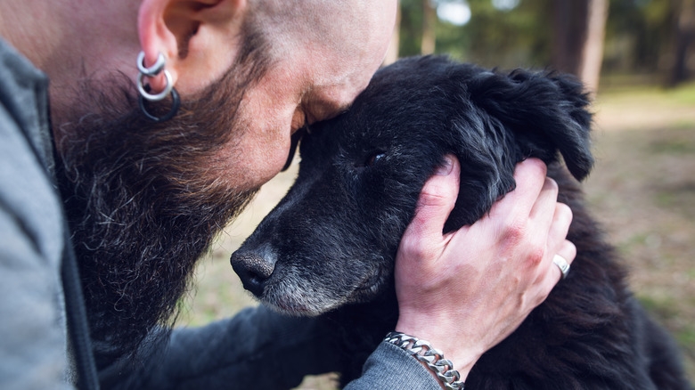 man hugs old dog