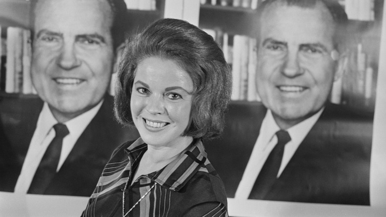 Shirley Temple in front of a poster of Richard Nixon