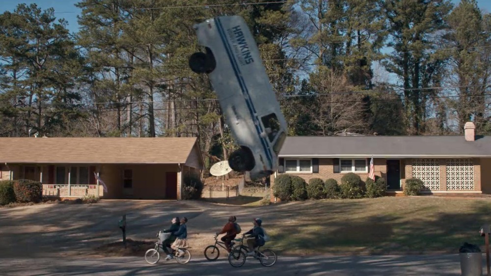 The kids on bikes while a van is flipping.