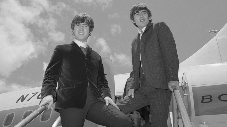 young George Harrison and John Lennon outside getting on a plane