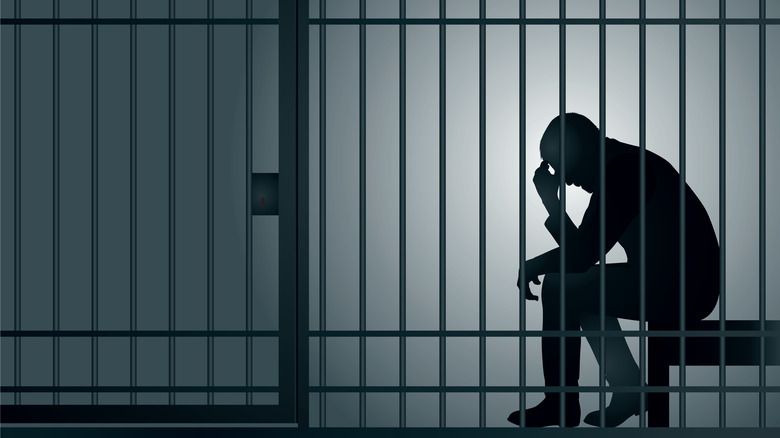 person sitting in a jail cell
