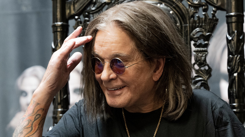 Ozzy Osbourne smiles and raises his hand