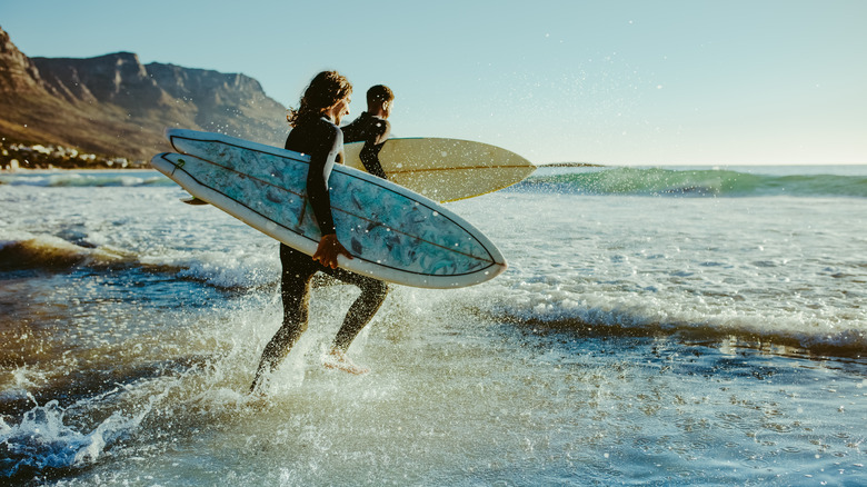 Two surfers running into the ocean