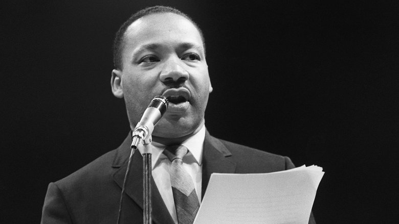 Martin Luther King Jr. speaking into mic in a suit