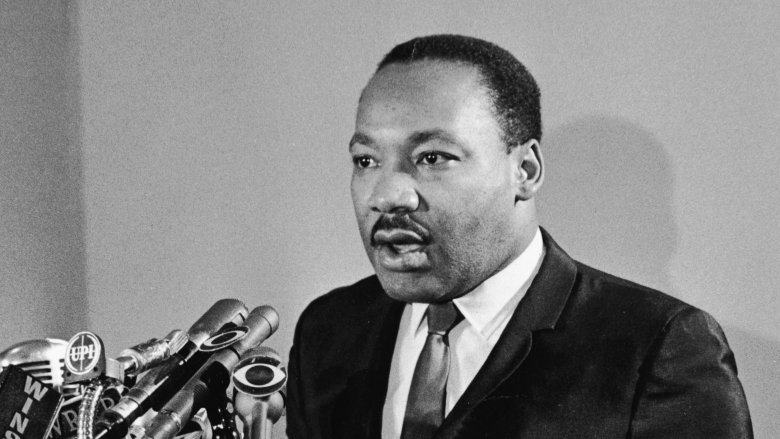 Martin Luther King Jr. talking into mics in suit