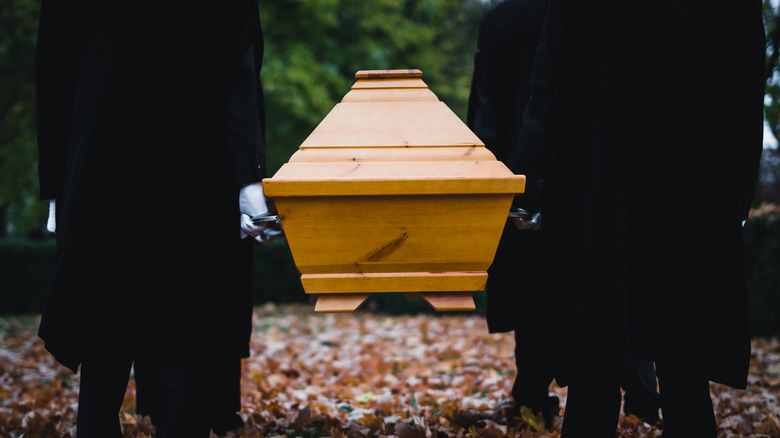 four people carrying coffin