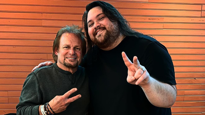 Smiling Michael Anthony posing with Wolfgang Van Halen for a photo