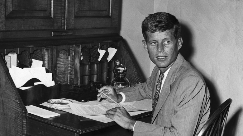 Young JFK sitting at a desk