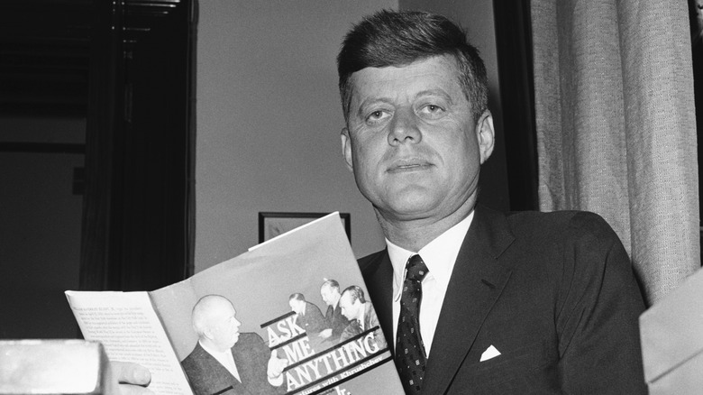 President Kennedy looks up from book