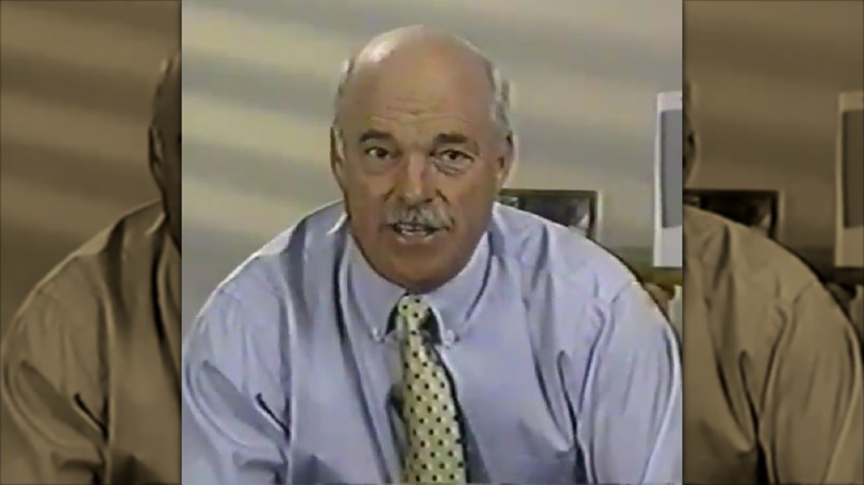 John Scherer seated at a desk speaking with computers in background