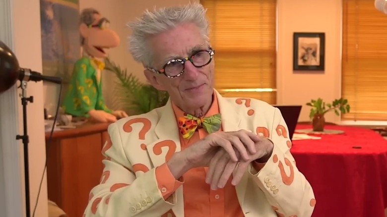 Matthew Lesko seated in an orange question mark suit