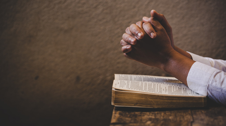 Folded hands on a Bible
