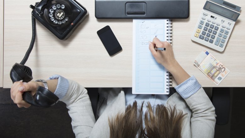 secretary writing holding phone desk