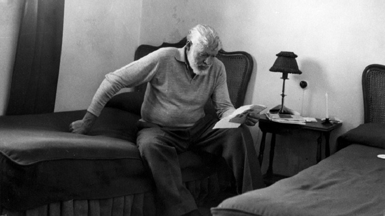 Ernest Hemingway sitting on bed