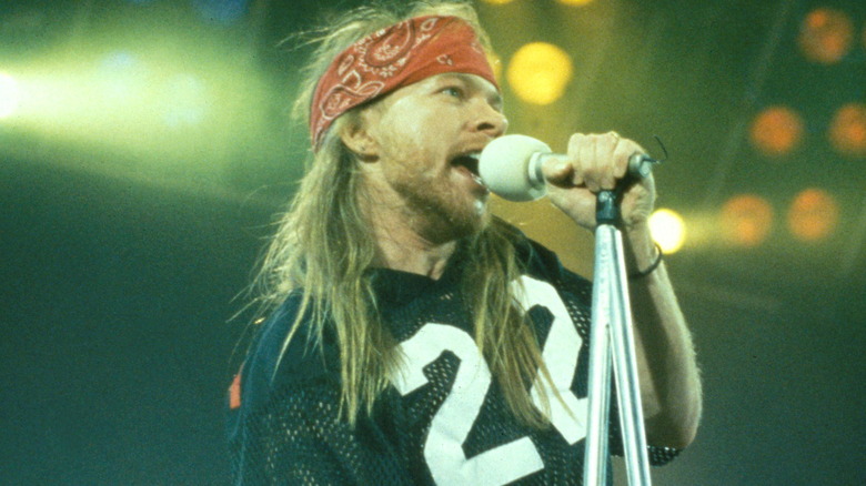 Axl Rose on stage singing in red bandana