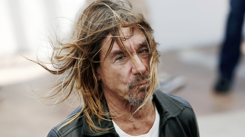 Iggy Pop in leather jacket and white shirt with hair blowing