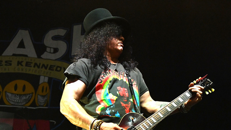 Guitarist Slash playing onstage with guitar and tophat