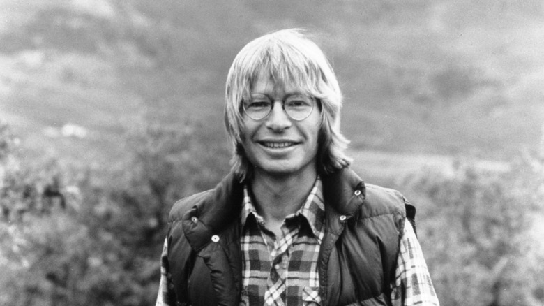 john denver smiling in front of a mountain