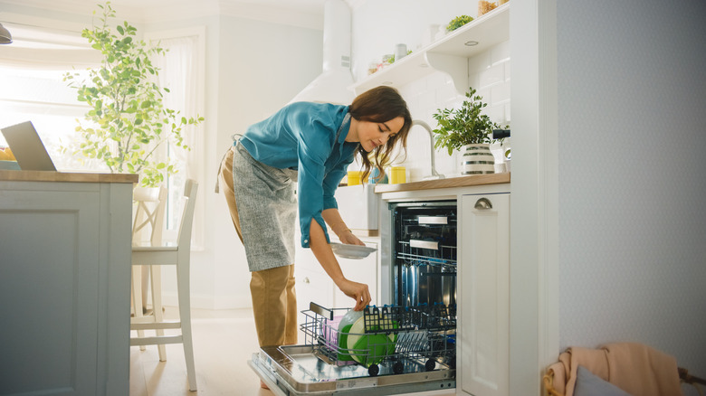 a woman using a dishwasher