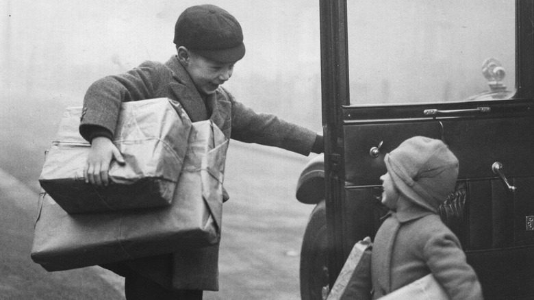 Boy holds car door open, 1930s